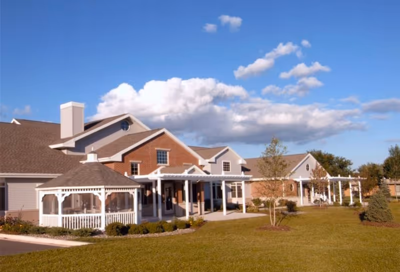 Sunny exterior view of a brick senior living center with white porches