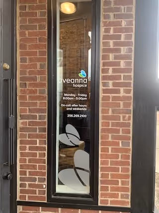 Glass door with Aveanna Hospice sign set in brick building entrance.
