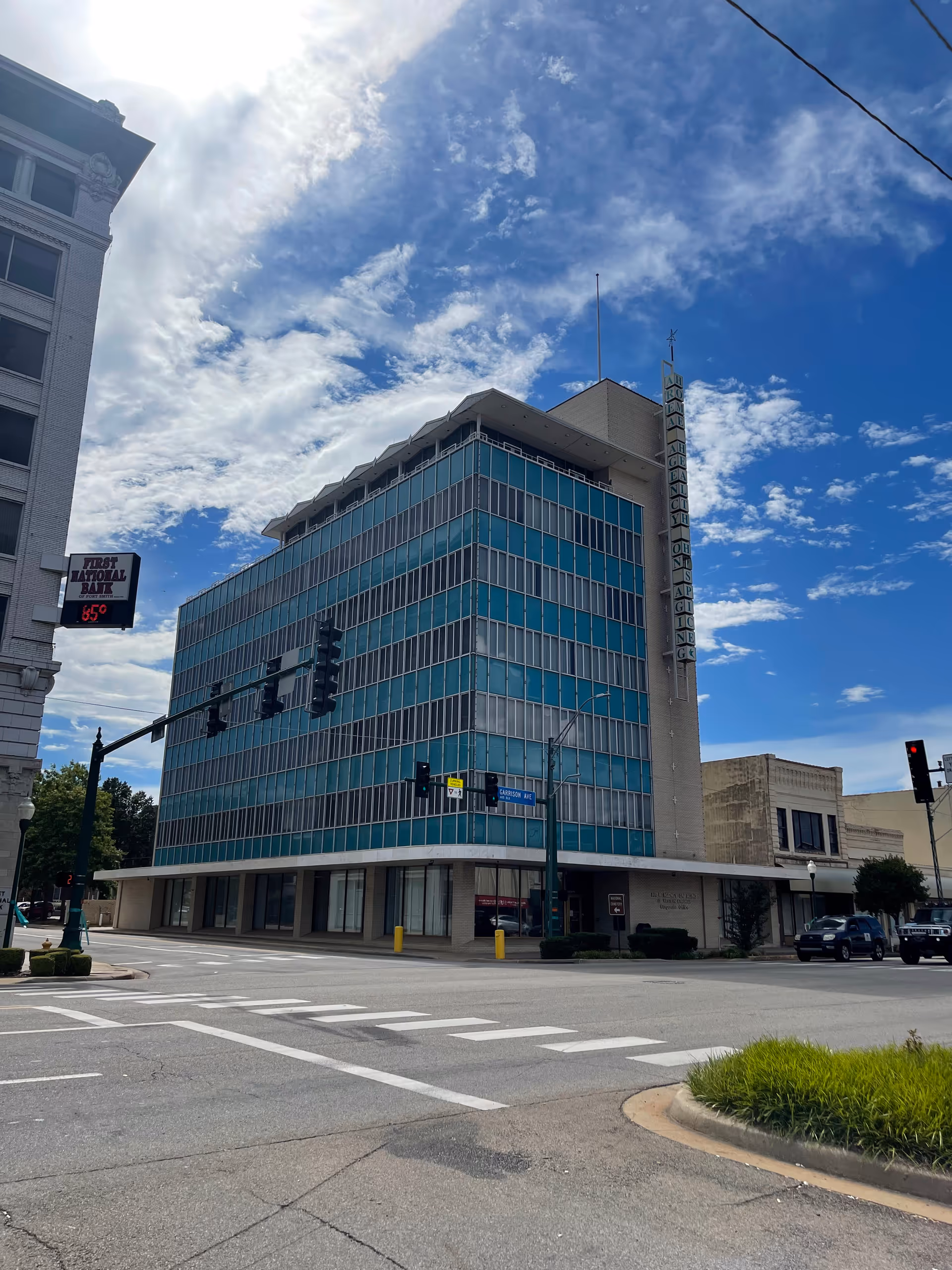 Tall glass-front building on a city street against a blue sky