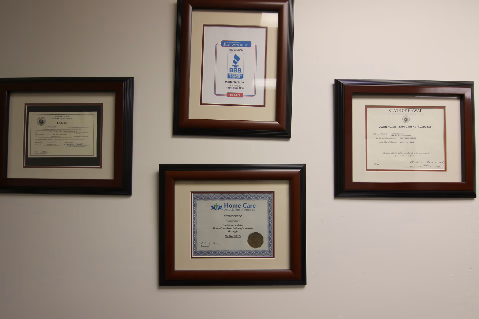 A wall with framed certificates and awards in dark wood frames.