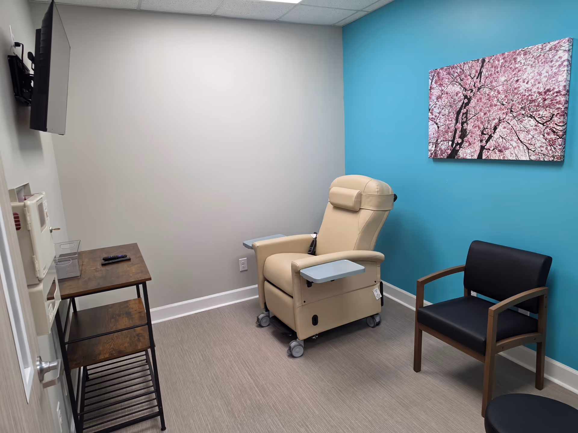 Infusion chair in a small treatment room with blue accent wall and seating.