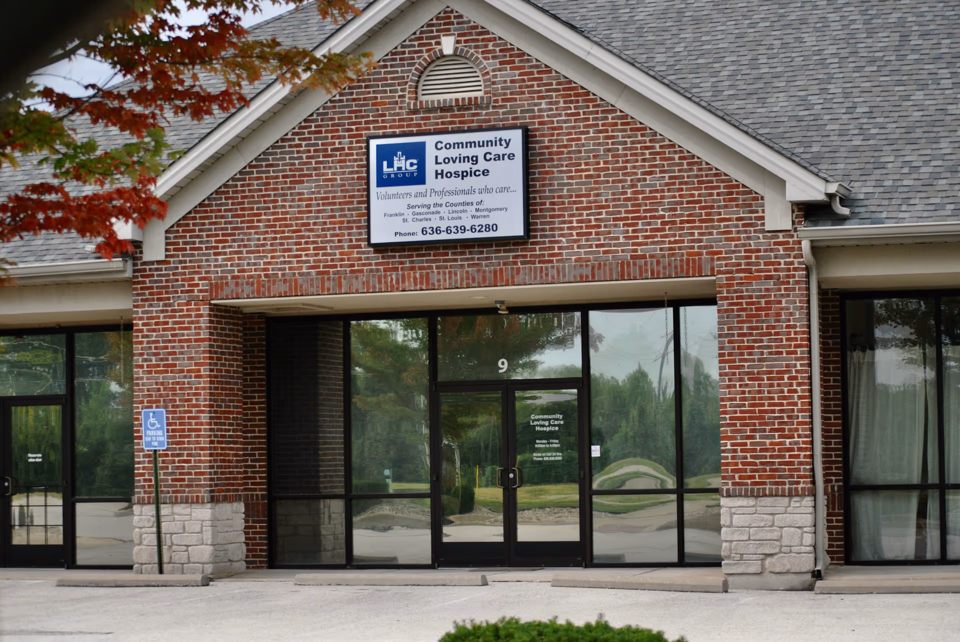 Brick building with glass entry doors and a sign reading Community Loving Care Hospice.