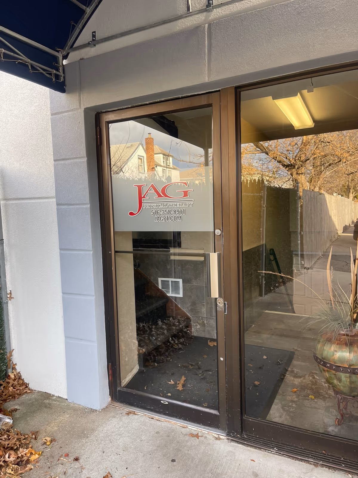 Glass door entrance displaying JAG Physical Therapy logo; outside walkway and leaves visible.
