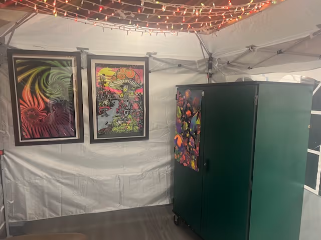 Interior tented room with string lights, framed art, and a large green cabinet.