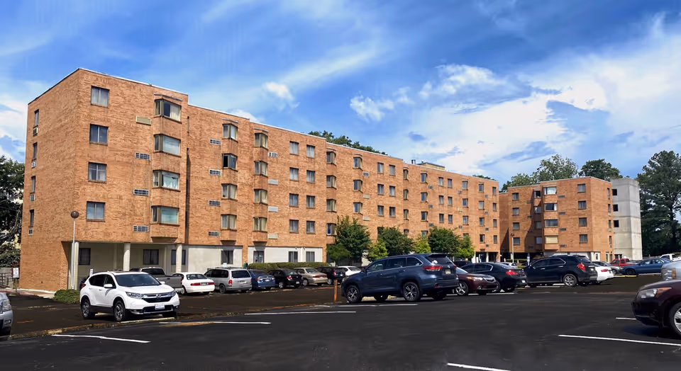 Brick multi-story Lakeland Seniors Apartments building with a parking lot under a blue sky.