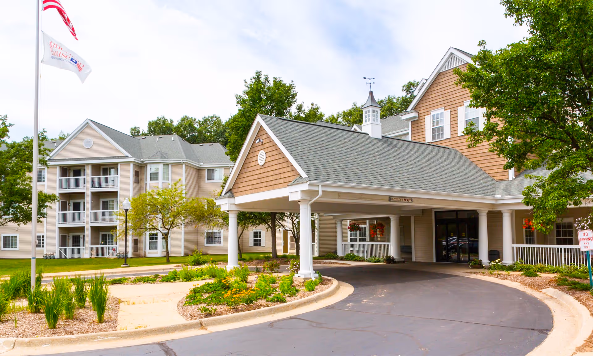 Exterior view of Grand Woods Senior Apartments showing a covered entrance and landscaped grounds.