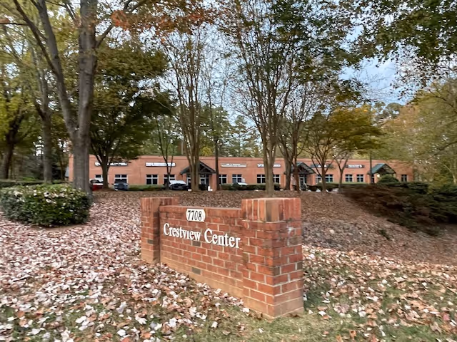 Brick sign for Crestview Center in front of a senior living facility surrounded by trees.