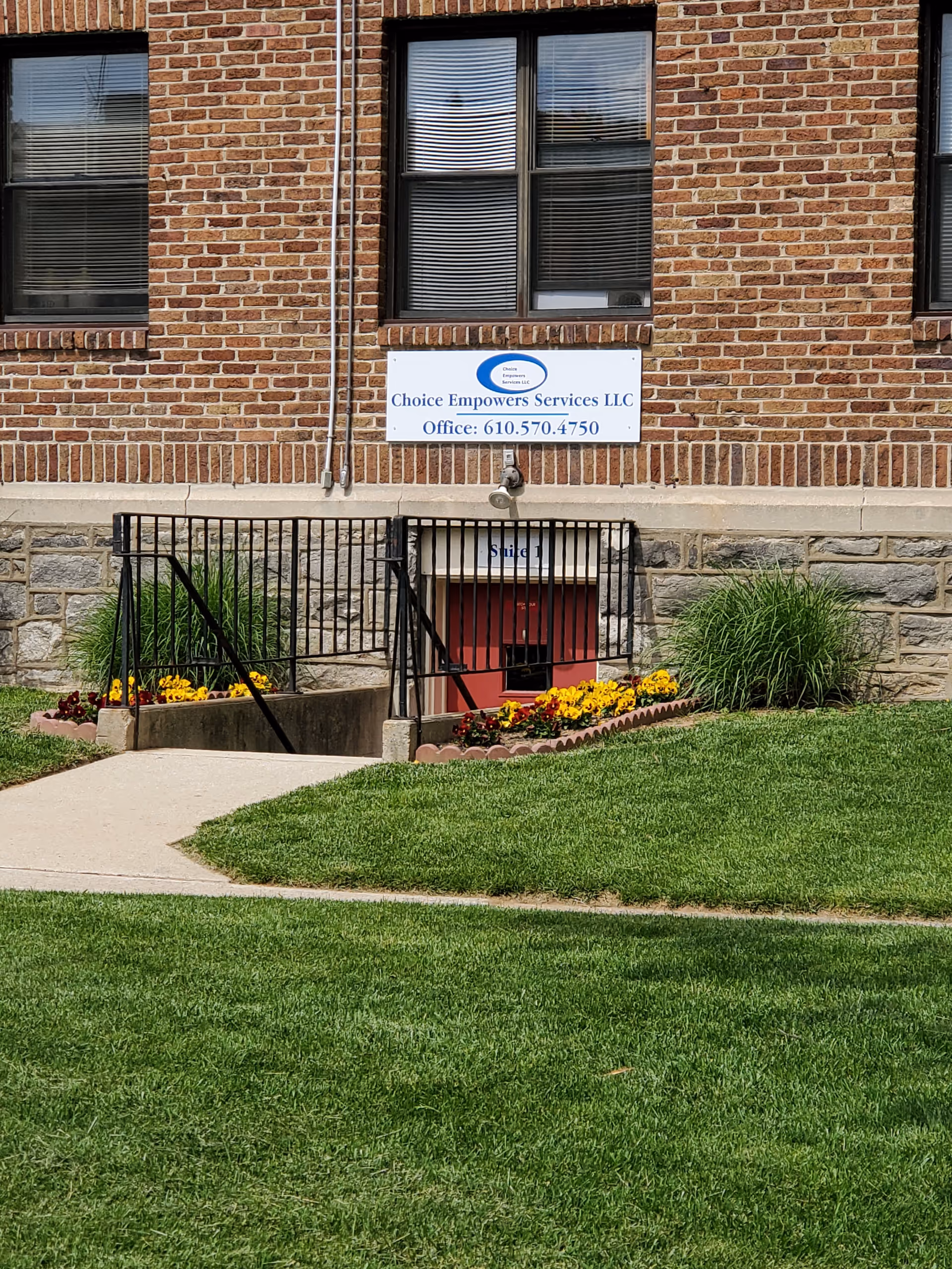 Brick building facade with a sign for Choice Empowers Services LLC and a landscaped front entrance.