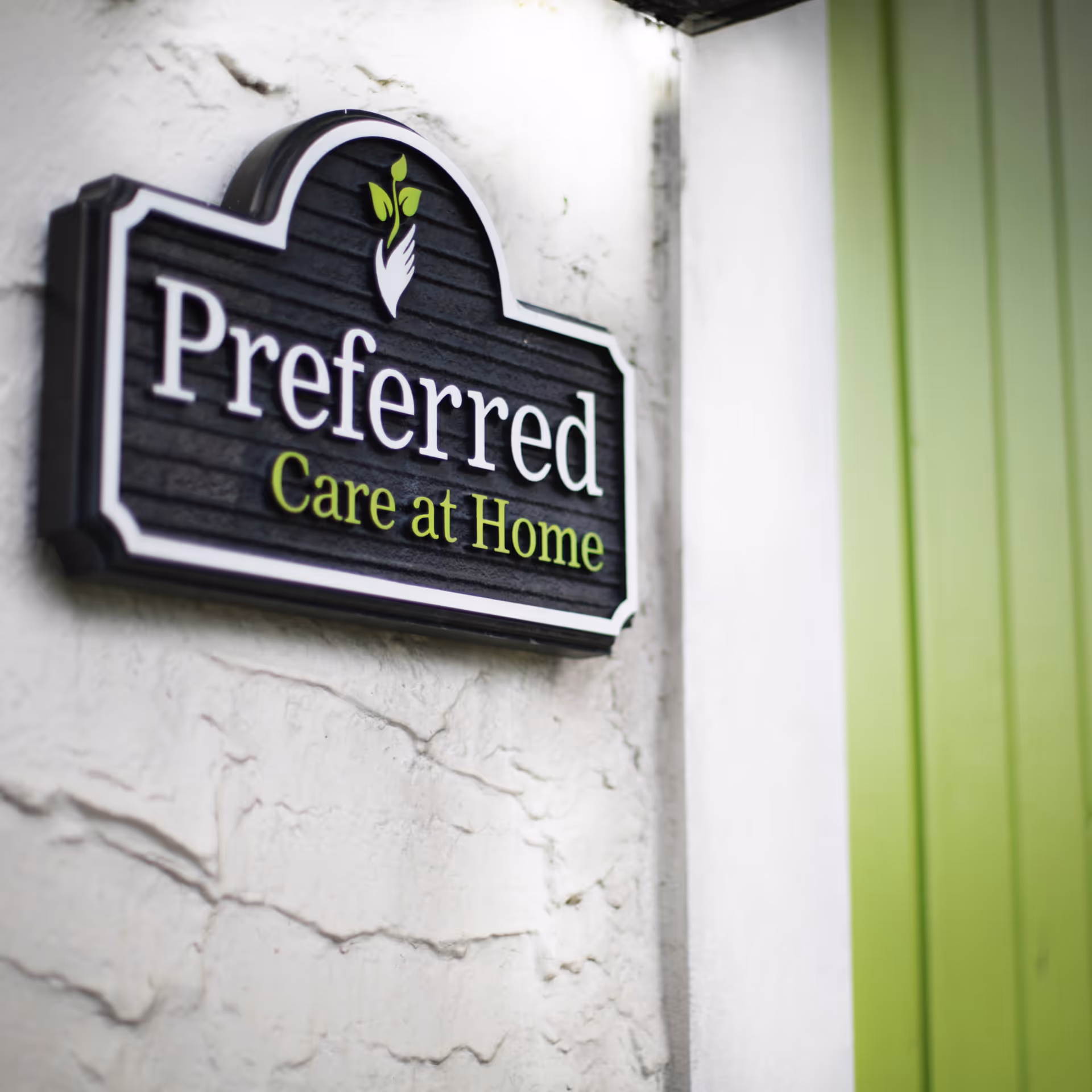 Sign on a textured wall reads 'Preferred Care at Home' with green accents