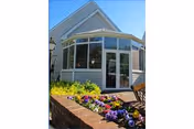 The Golden Crest facility entrance with bay windows, white siding, and a colorful flower bed.