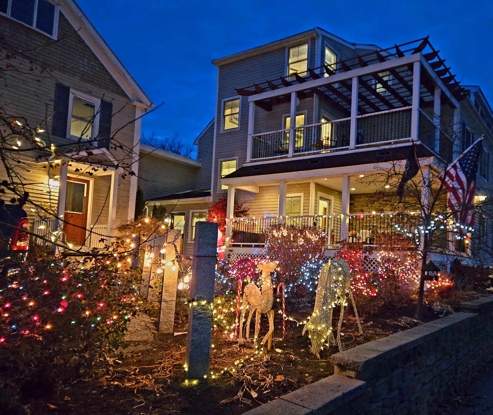 Two-story assisted living building at night, front yard lit with colorful holiday lights and decorations.