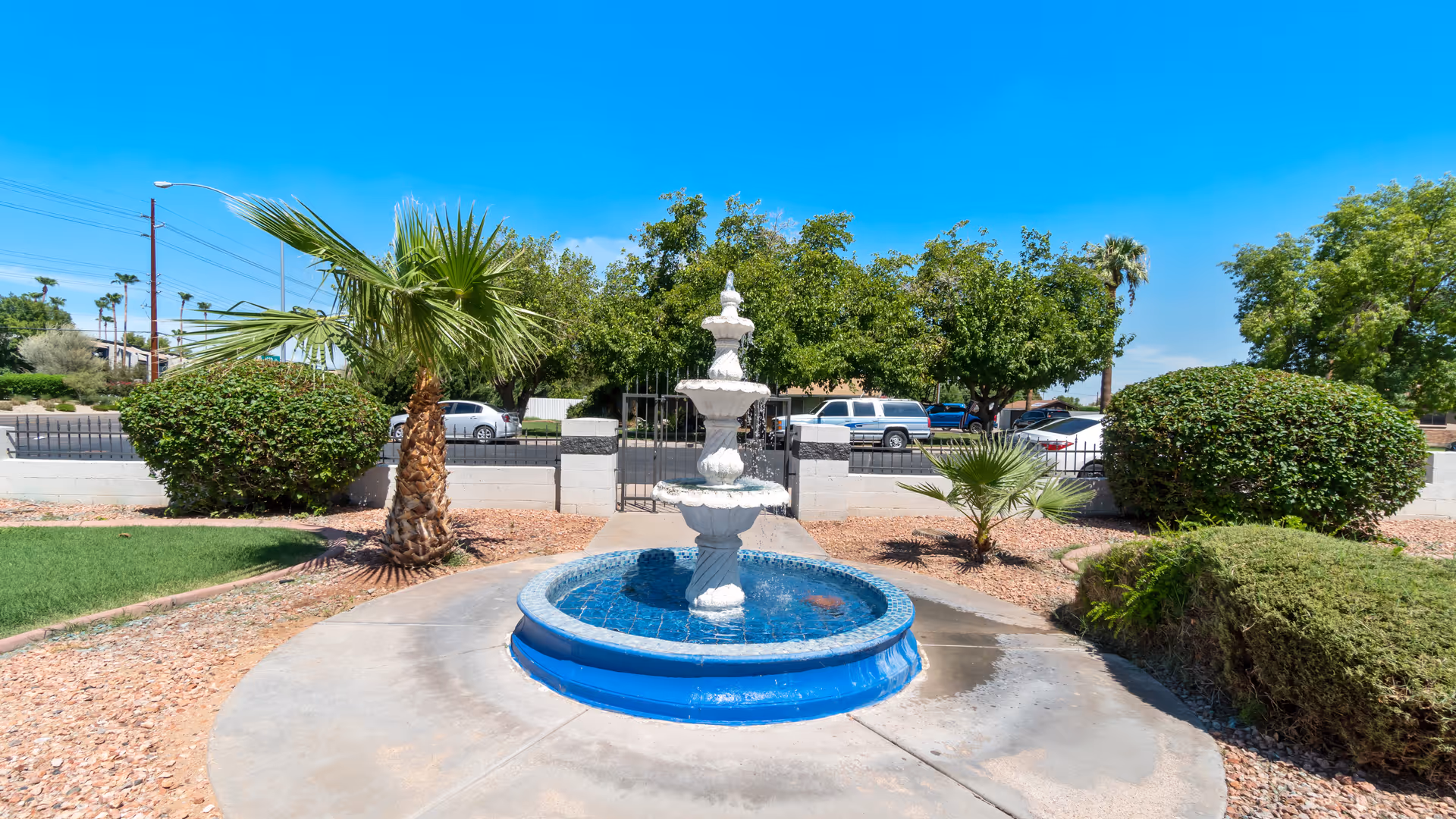 A white multi-tier fountain in a sunny outdoor courtyard at Jones Family Care Home.