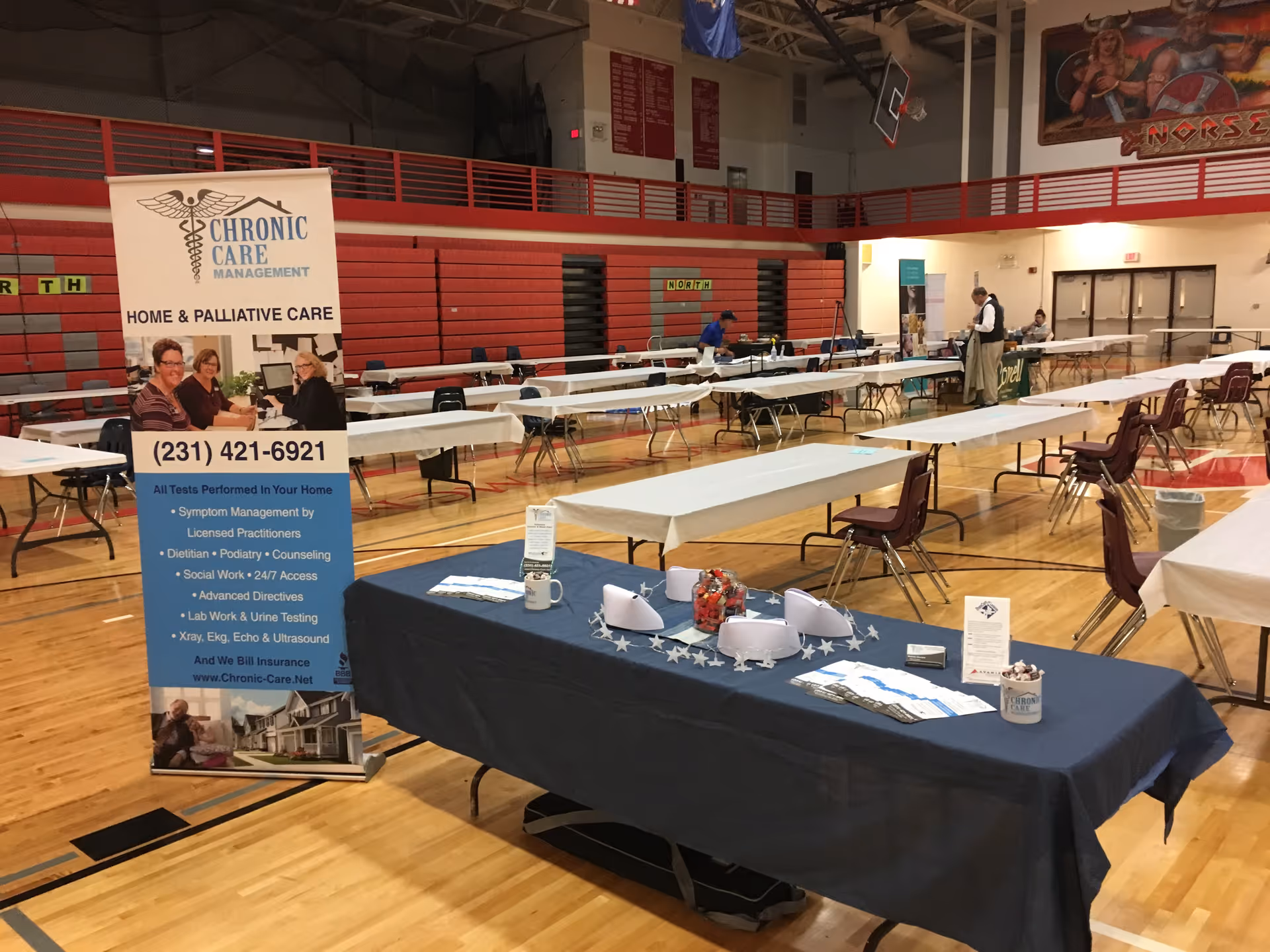 Indoor gym setup with long tables, chairs, and a Chronic Care Management banner.
