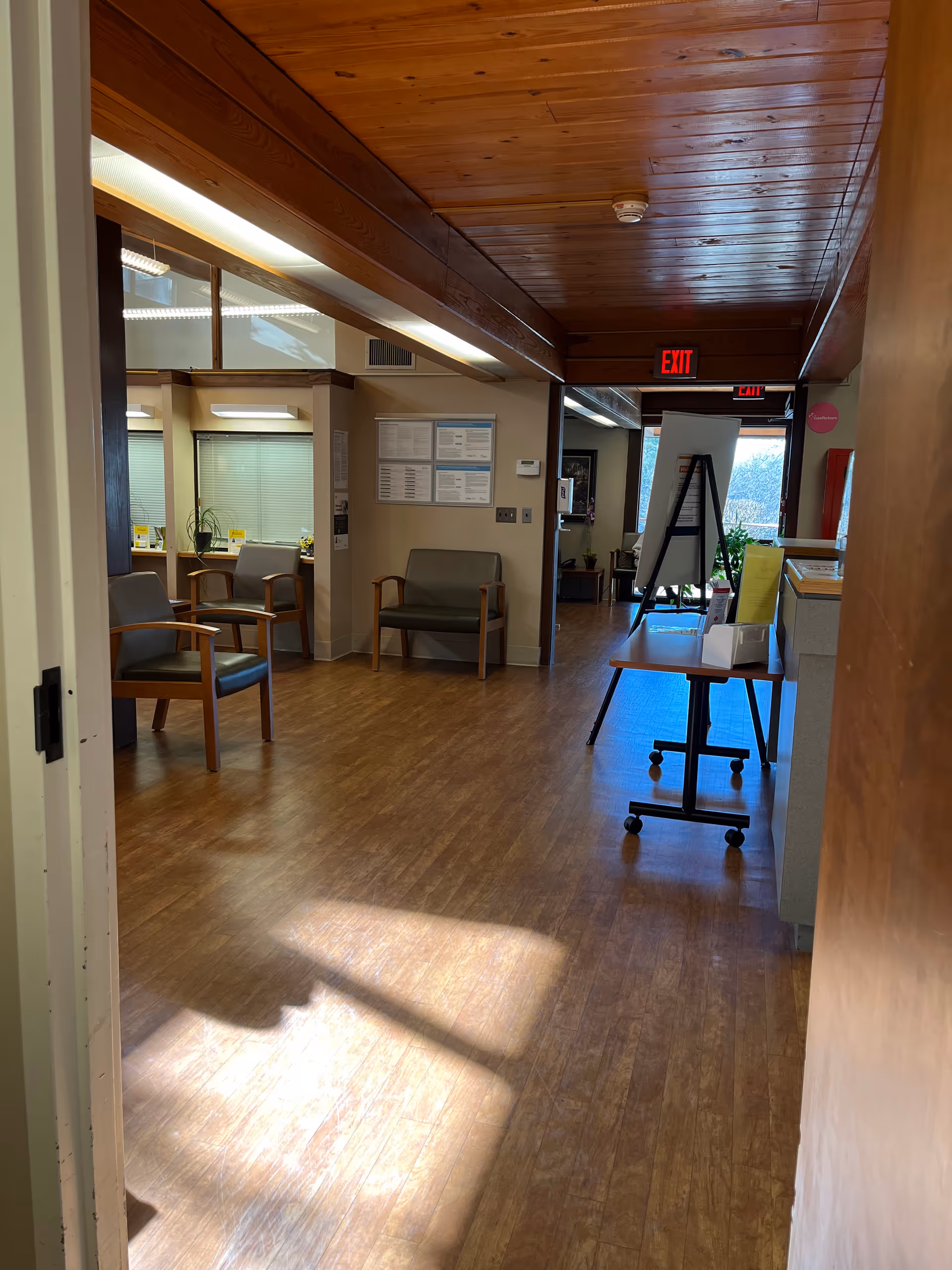 Wood-paneled interior lobby with chairs, a movable table, and an exit sign.