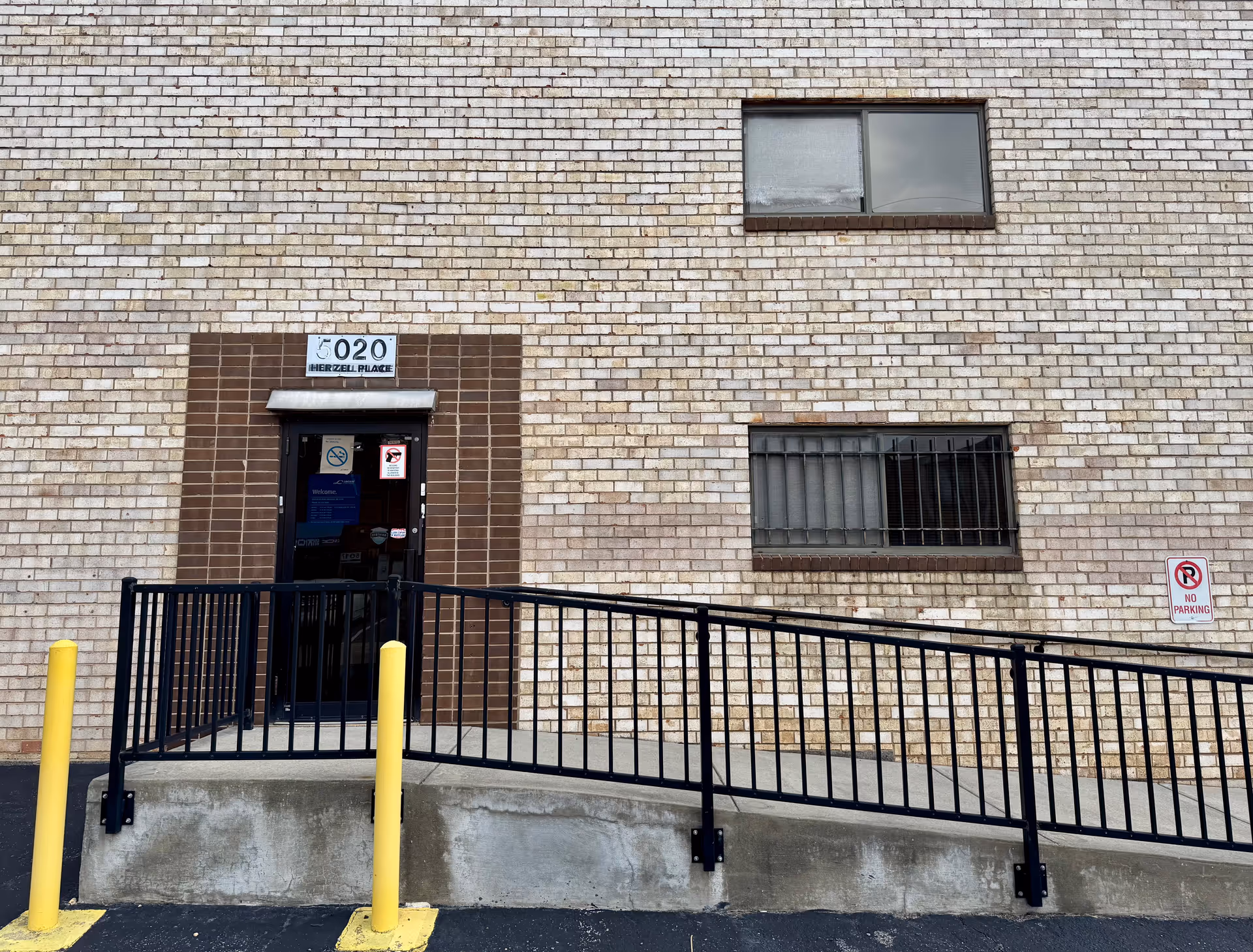 Brick exterior of a facility with a ramp, railing, and doorway entrance.