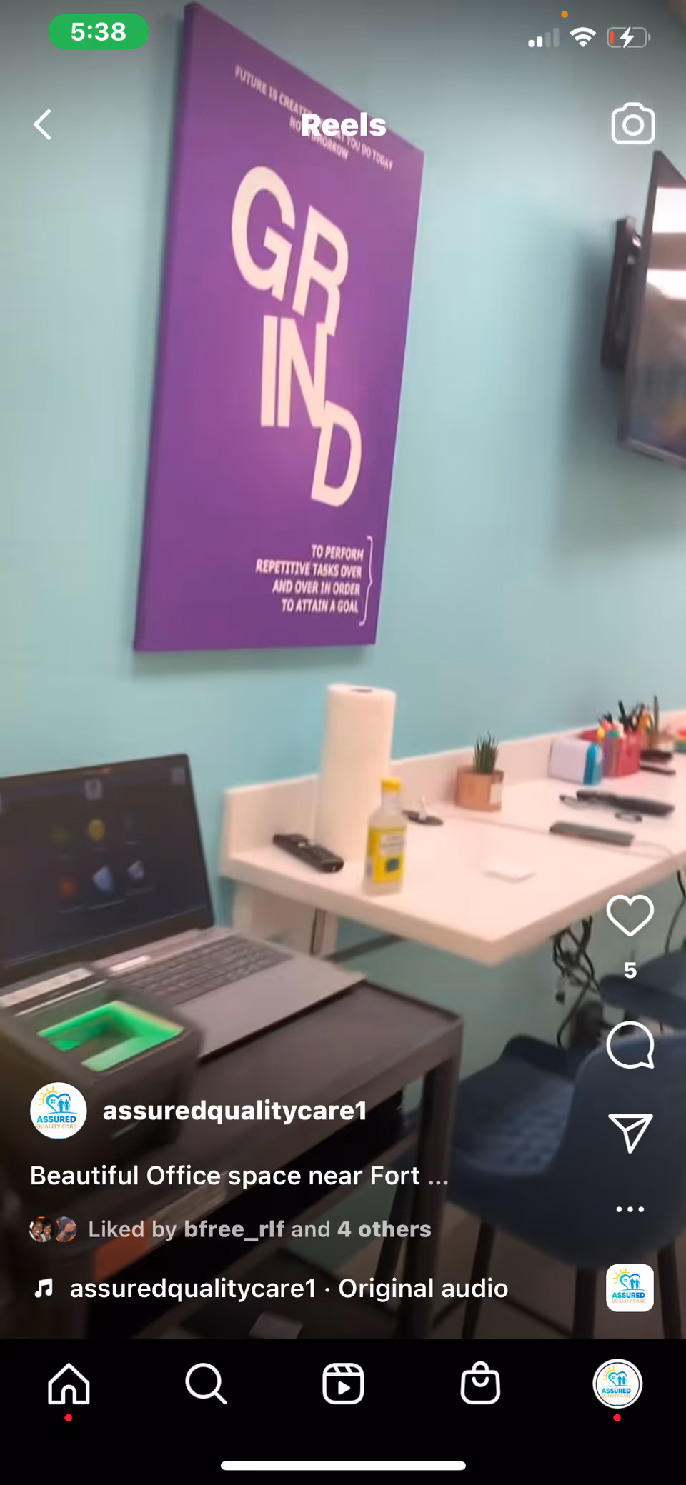A compact office workspace with a laptop, supplies, and a purple poster on a teal wall.