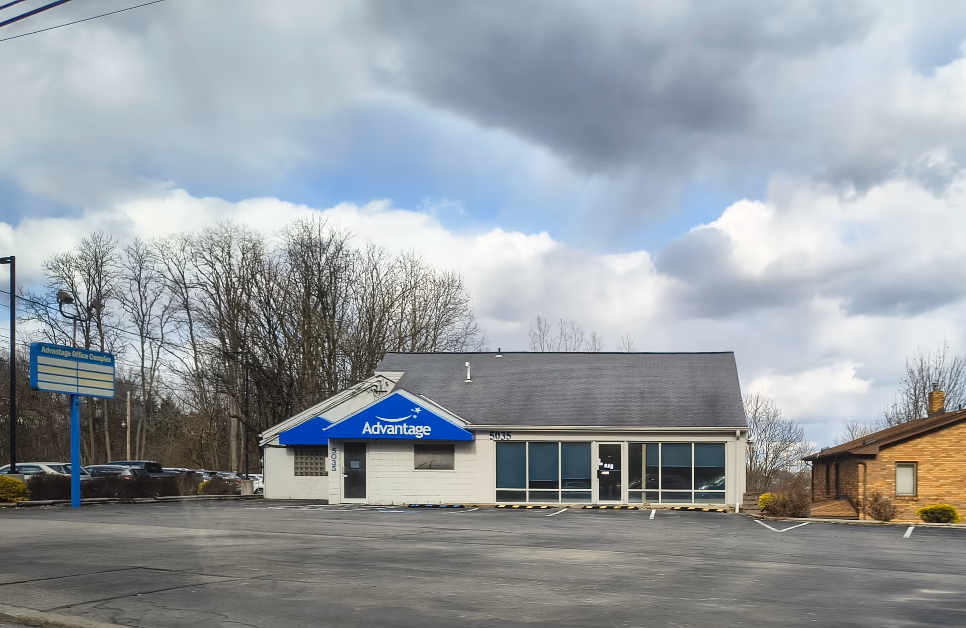 Front view of AdvantageCare Rehabilitation building with blue awning and parking lot.