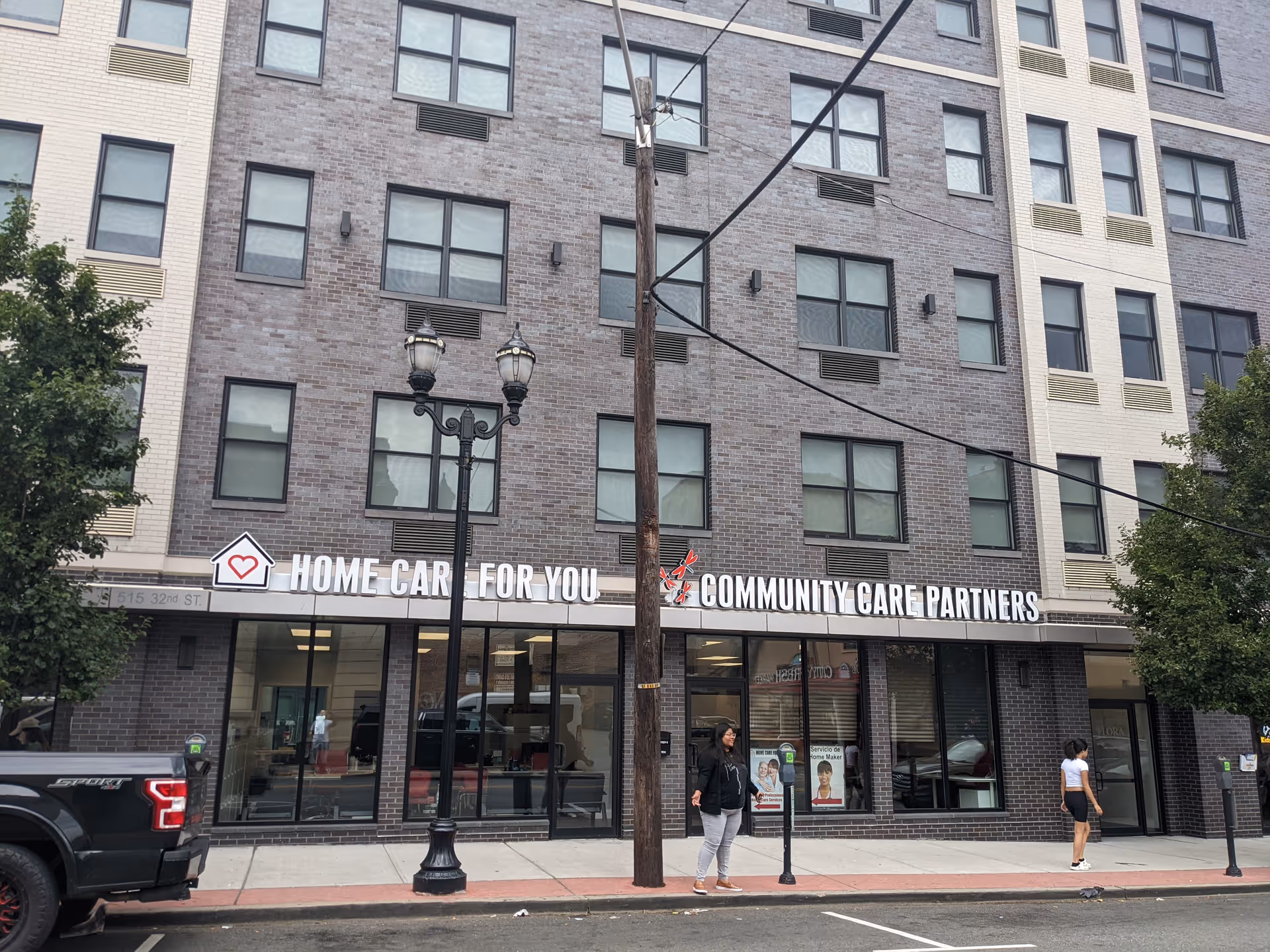 Brick storefront building with 'Home Care For You' sign along the sidewalk.