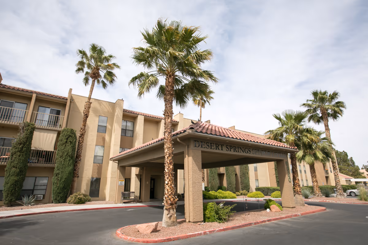 Exterior view of Desert Springs Senior Living facility entrance with palm trees.