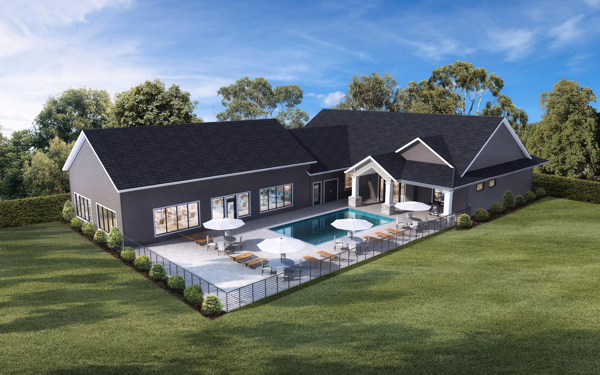 Aerial view of a single-story community building with a fenced outdoor pool, lounge chairs, and umbrellas surrounded by grass and trees.