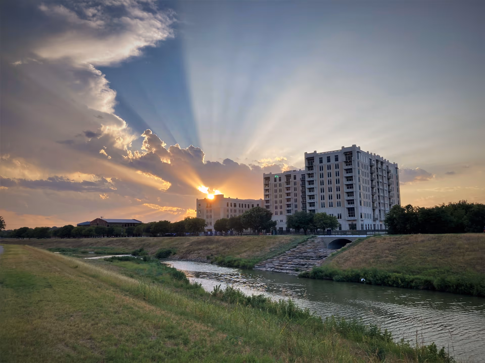 Sunset over a modern senior living building beside a river