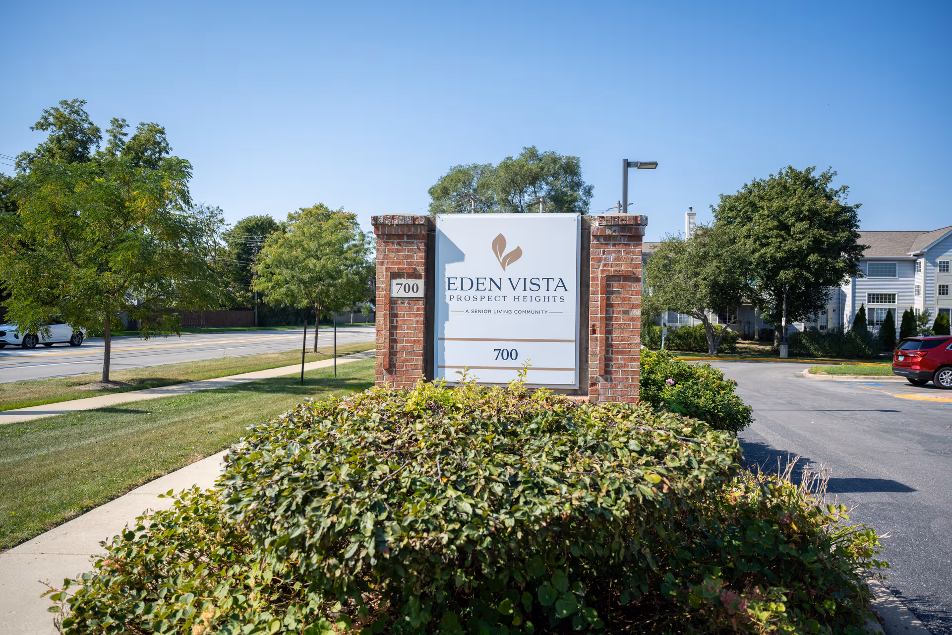 A brick-entry sign for Eden Vista Prospect Heights stands among landscaped shrubs.