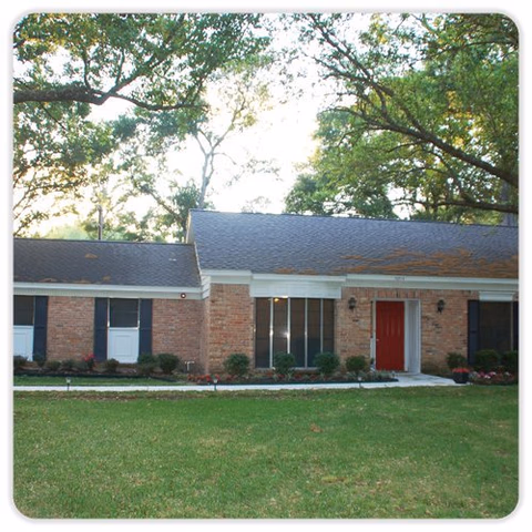 Exterior view of Cypress Assisted Living: single-story brick building with red door, lawn, and trees.