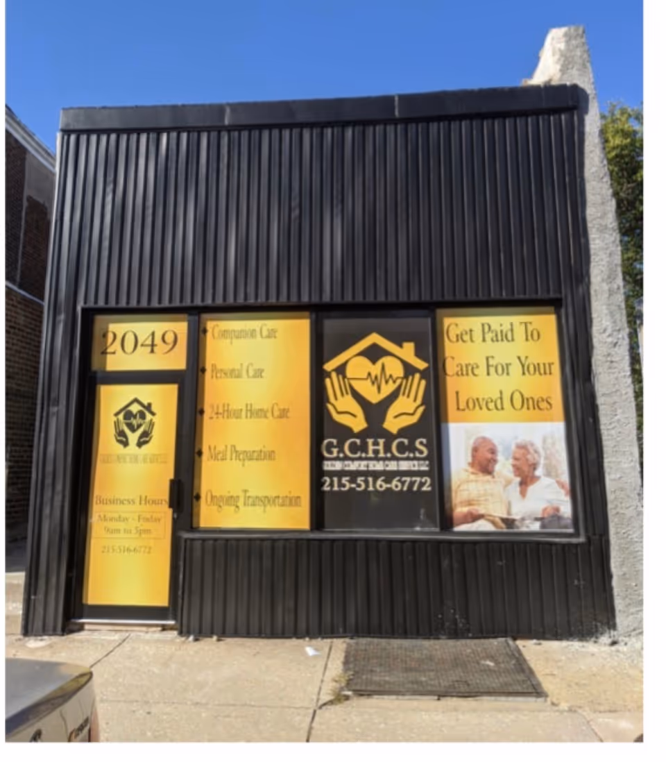 Front exterior of a black building with yellow promotional signs and logo on windows.