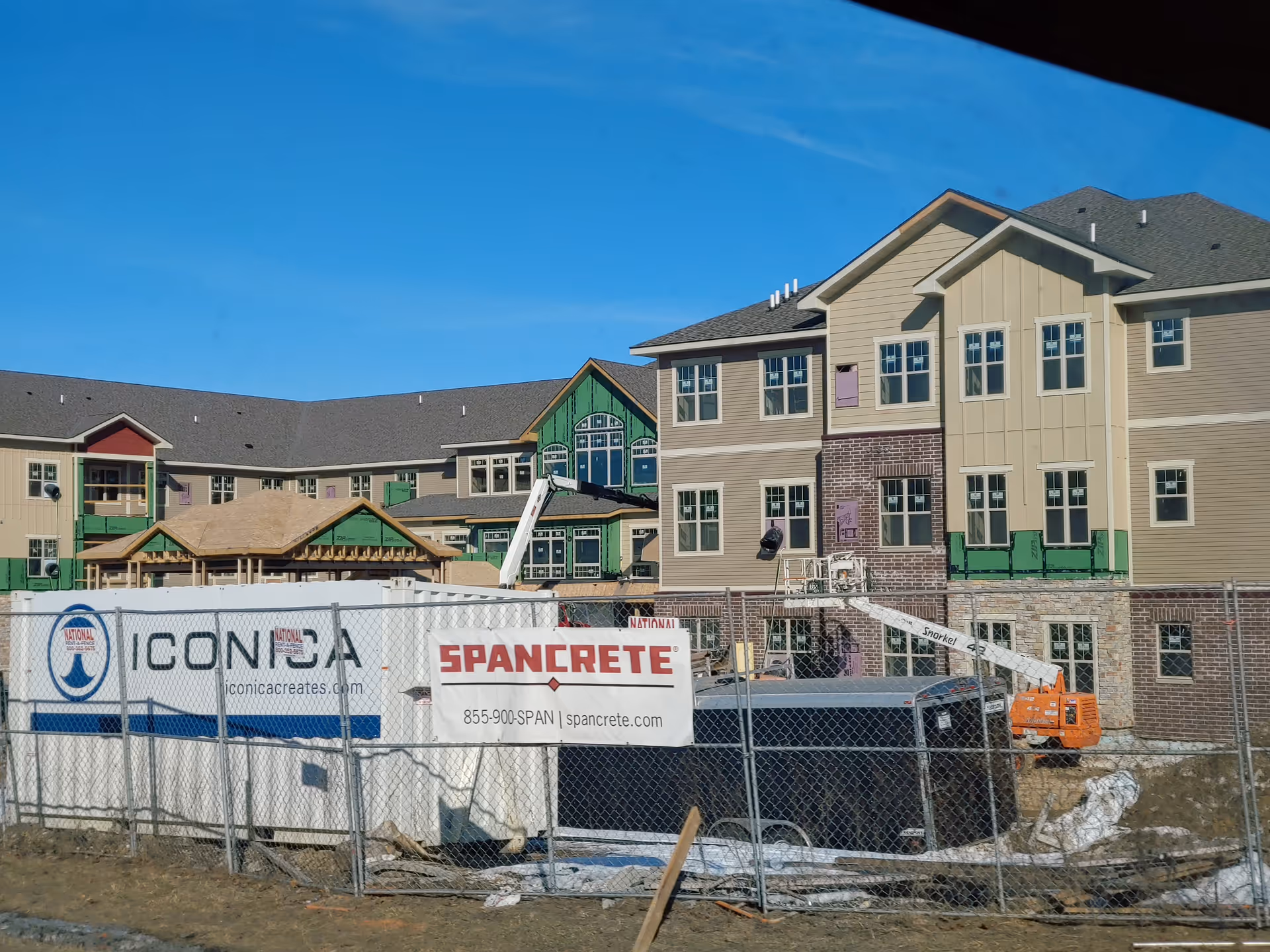 Under-construction New Perspective Waukesha senior living facility with fencing and construction equipment.