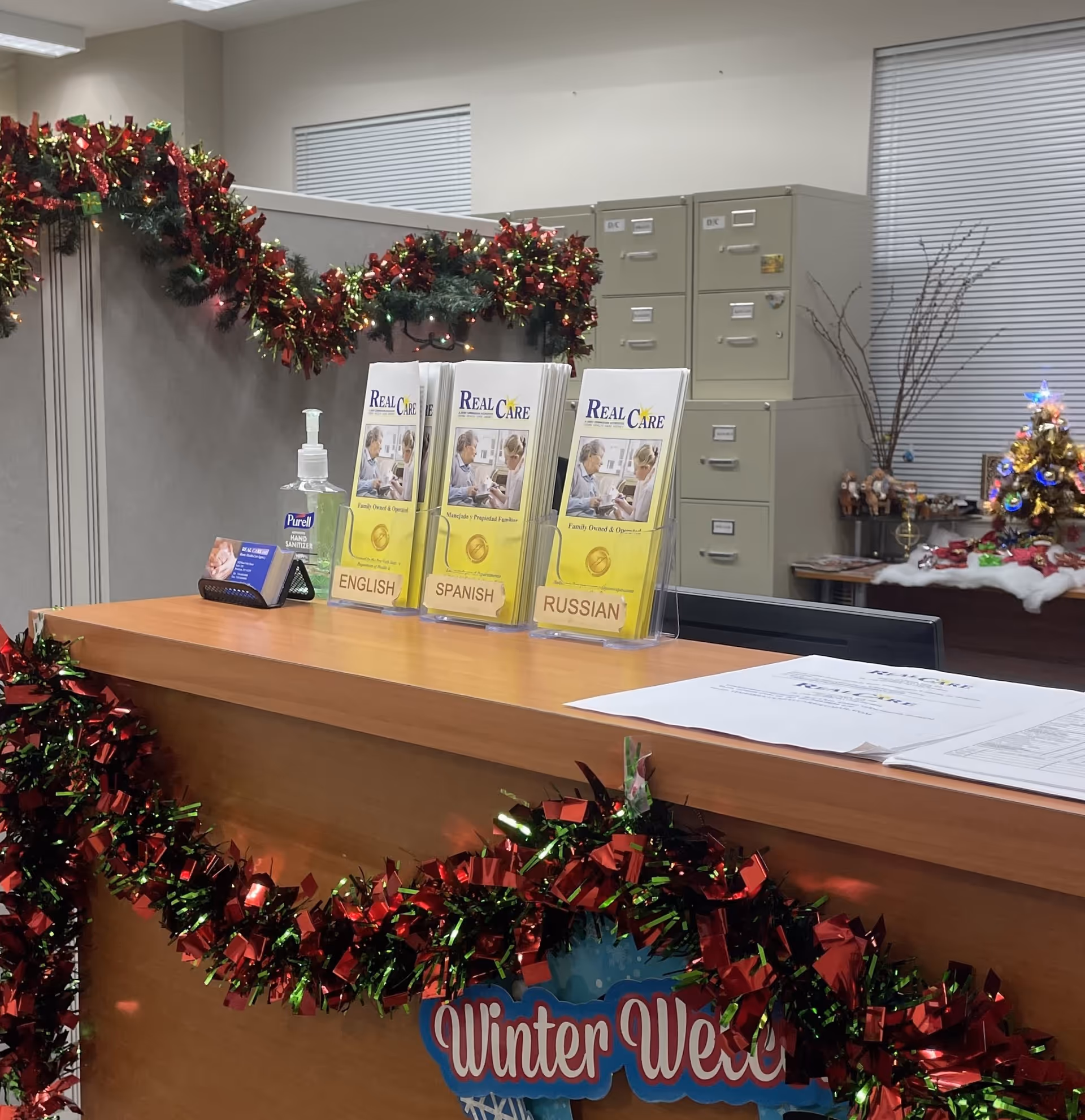 Front desk area decorated for holidays with brochures, garlands, and a small Christmas tree.