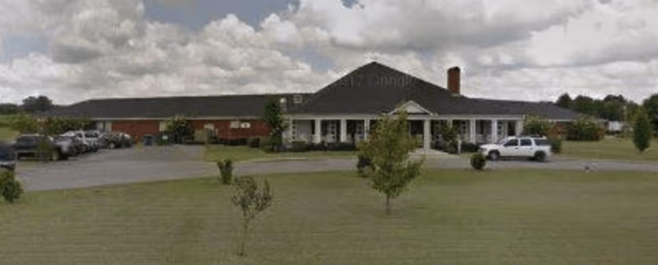 Front view of a single-story senior living facility with a parking lot.