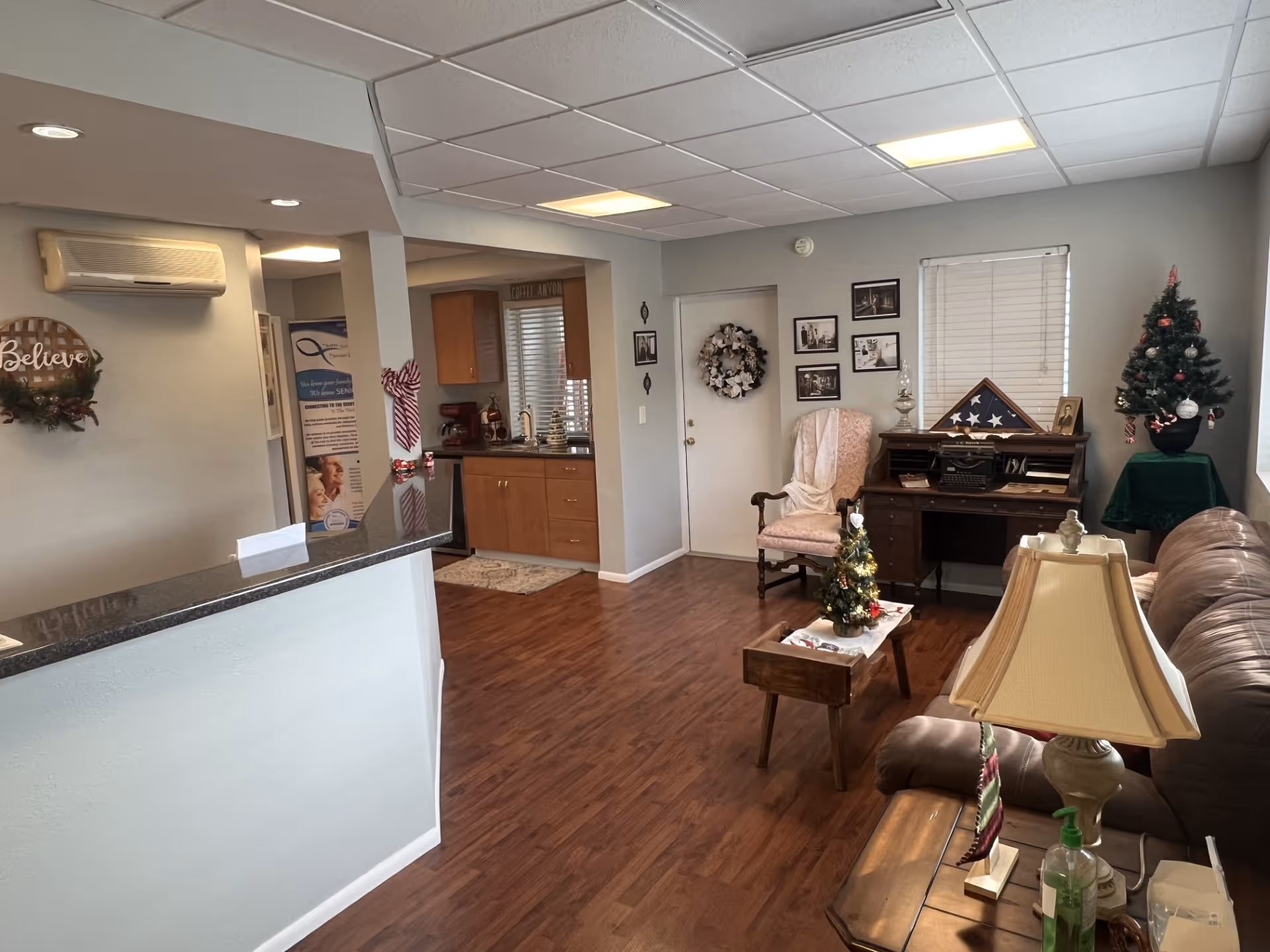Cozy senior living common area with sofa, piano, Christmas tree, and framed photos.