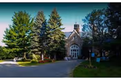St. Joseph's Adult Care Home exterior: stone building with arched entrance and tall trees.