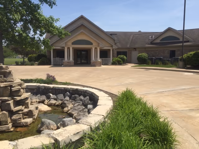 Front entrance of Evenglow Inn with curved driveway, landscaping, and a rock water feature.