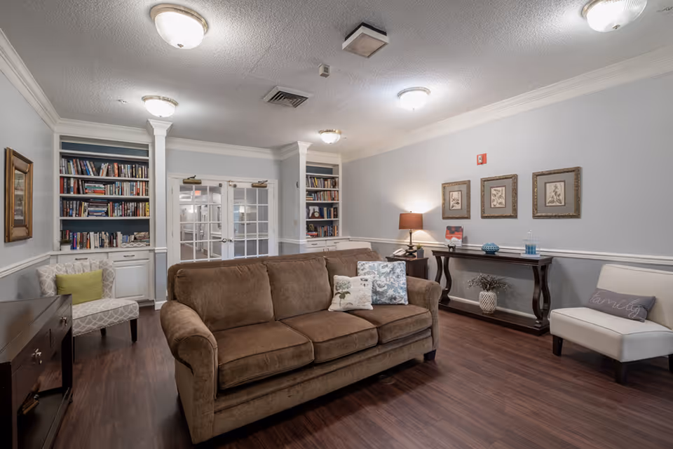 Cozy living room in a senior facility with sofa, bookshelves, and a console table.