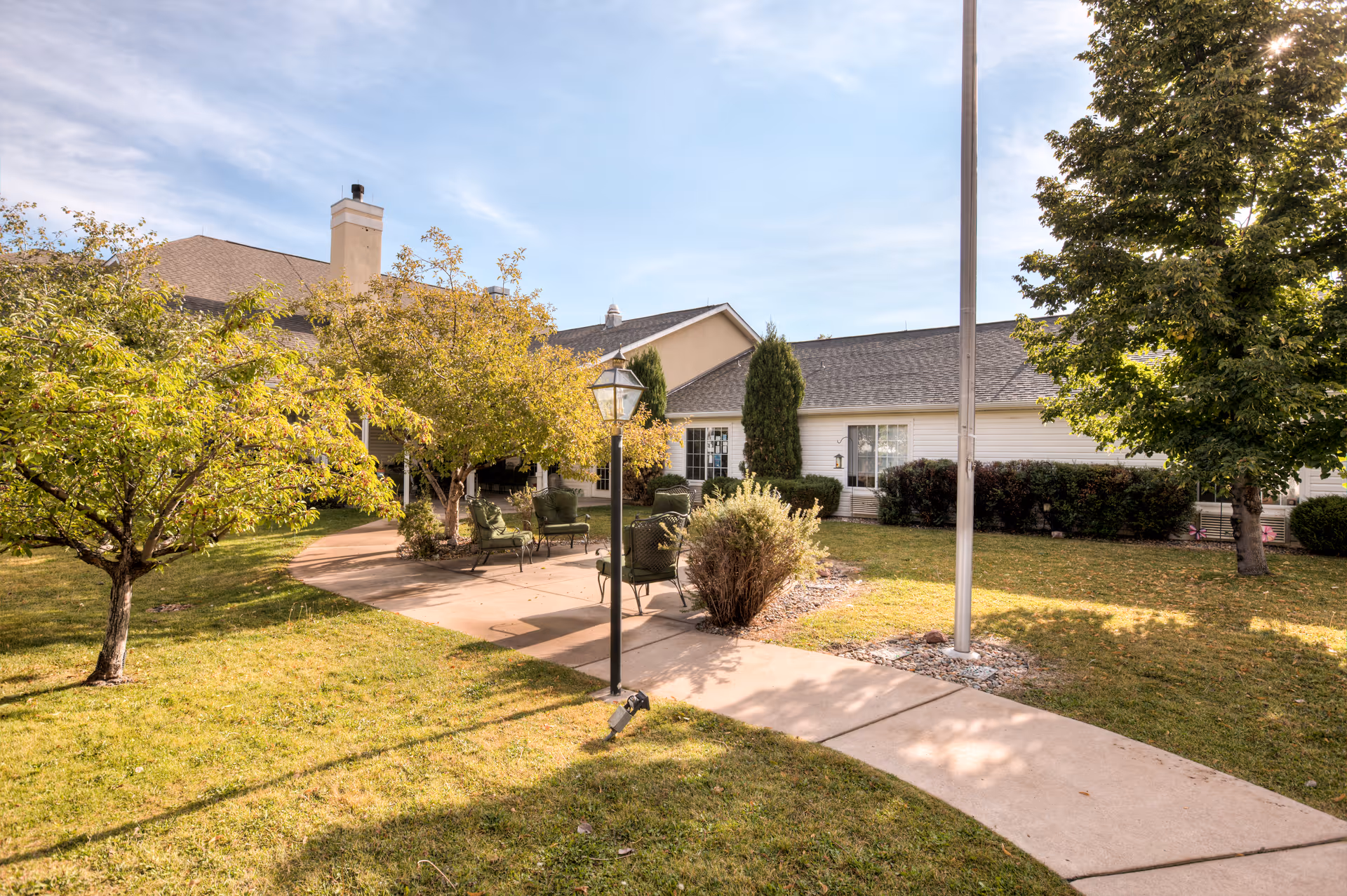 Outdoor courtyard with seating, path, lamp post, trees, and the Brookdale Broadmoor building.