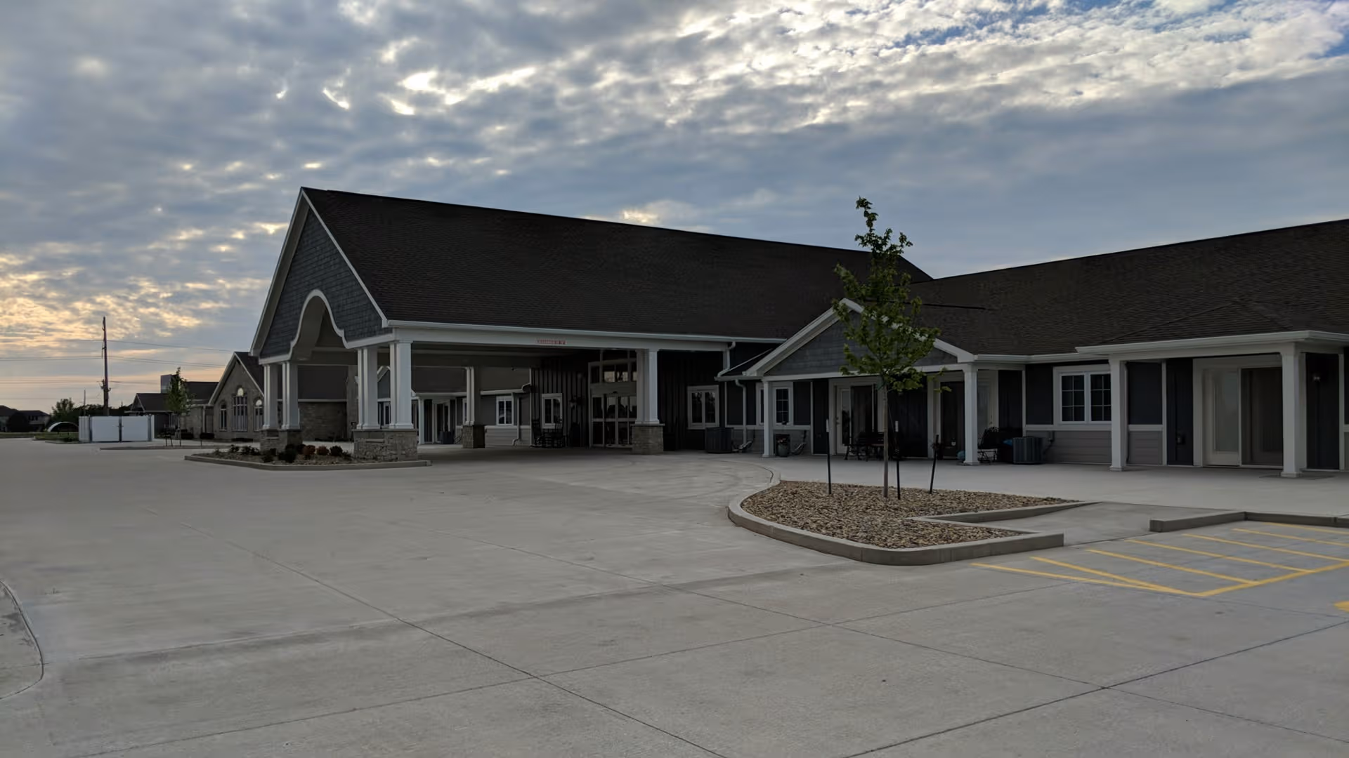Exterior view of a senior living facility with a covered entrance and parking.