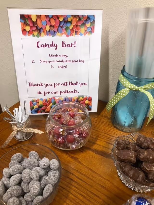Candy bar display on a wooden table with bowls of candy and a sign.