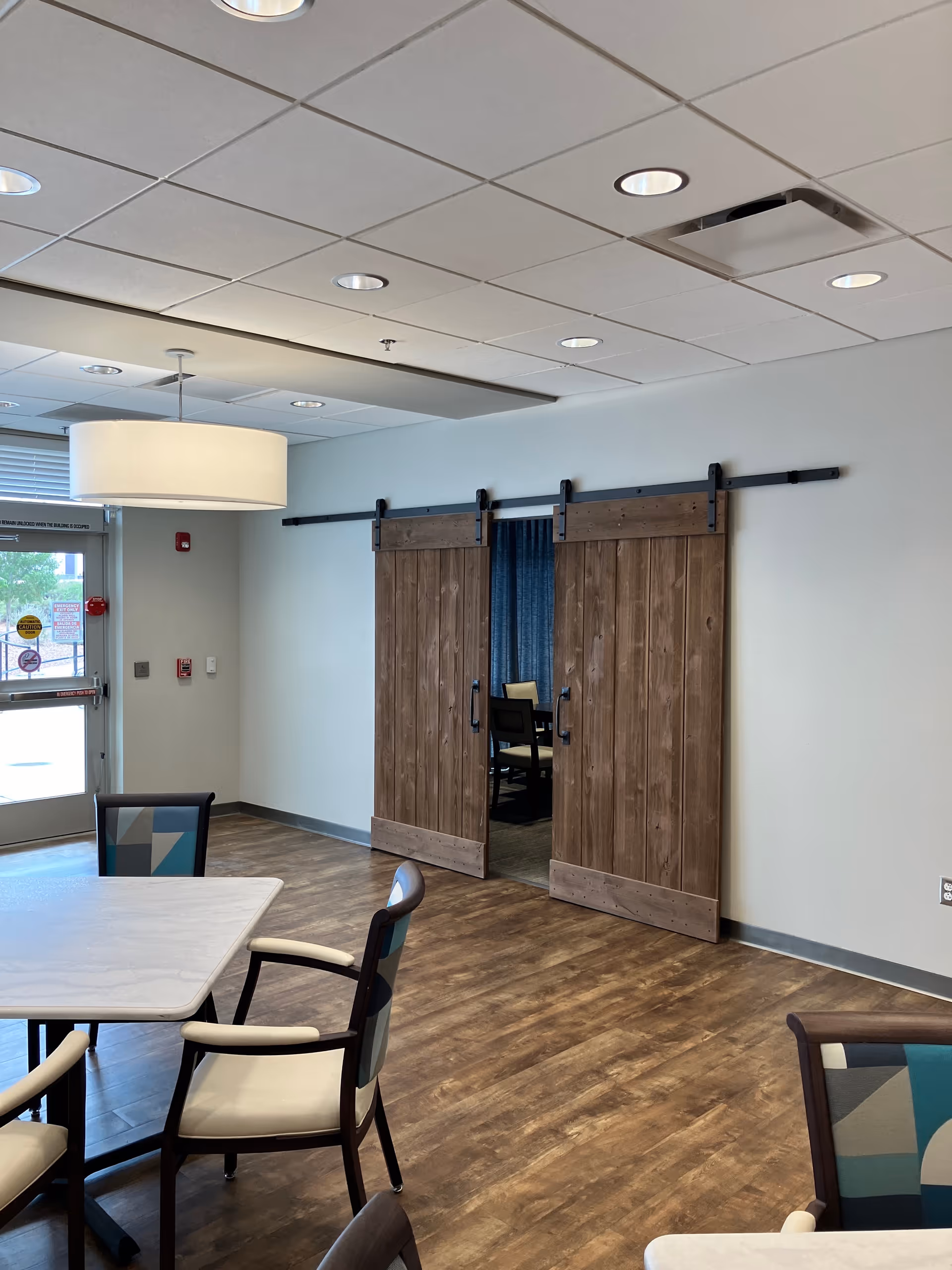Interior common area with wood barn doors, a dining table, and surrounding chairs.