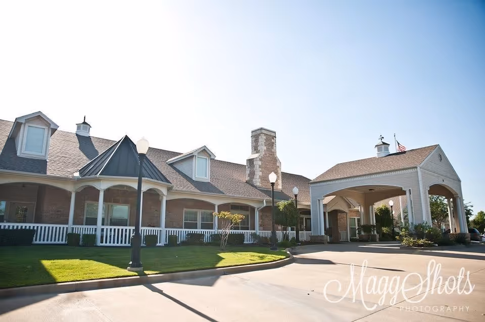 Exterior view of a brick senior living facility with a covered entrance and lawn.