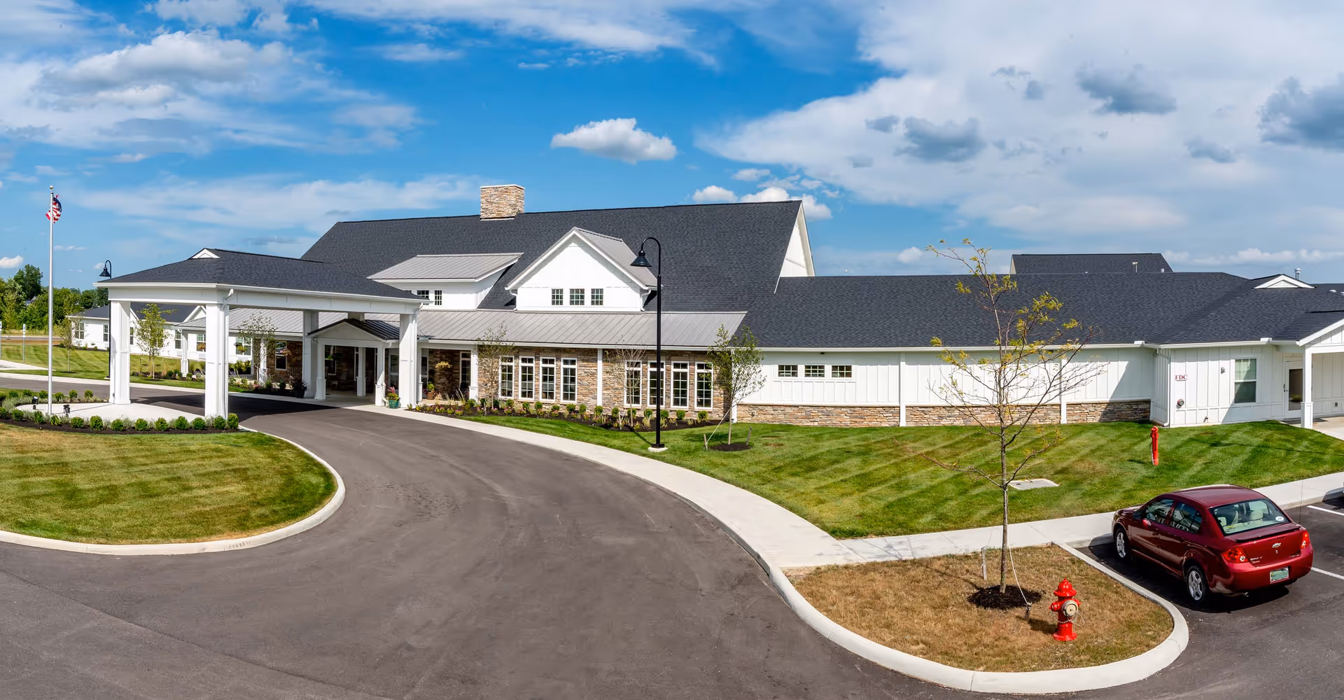 Exterior view of Walnut Crossing senior living facility with curved driveway, entrance canopy, and a car.