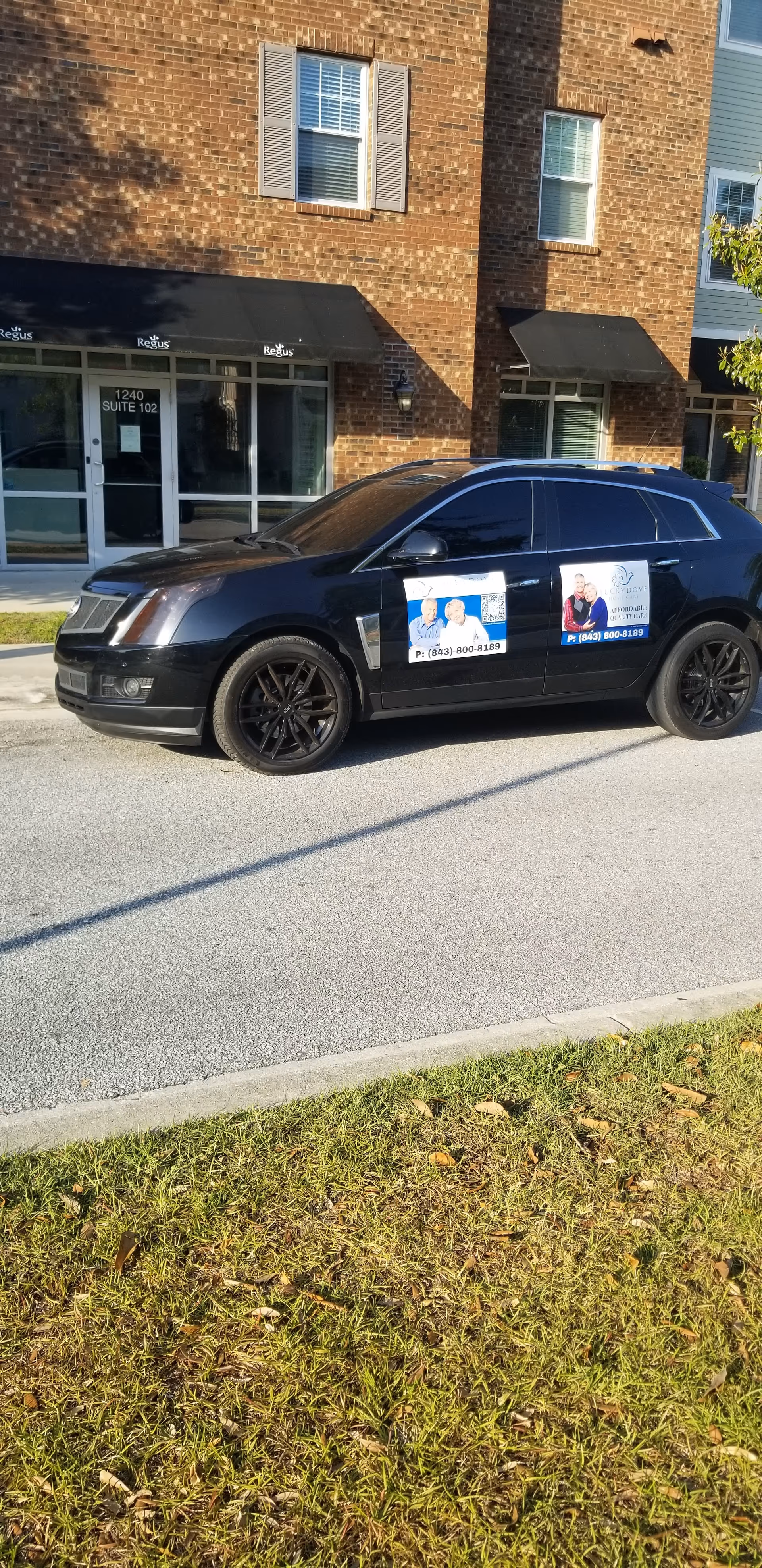 Black SUV with Lucky Dove Home Care posters parked in front of a brick building.
