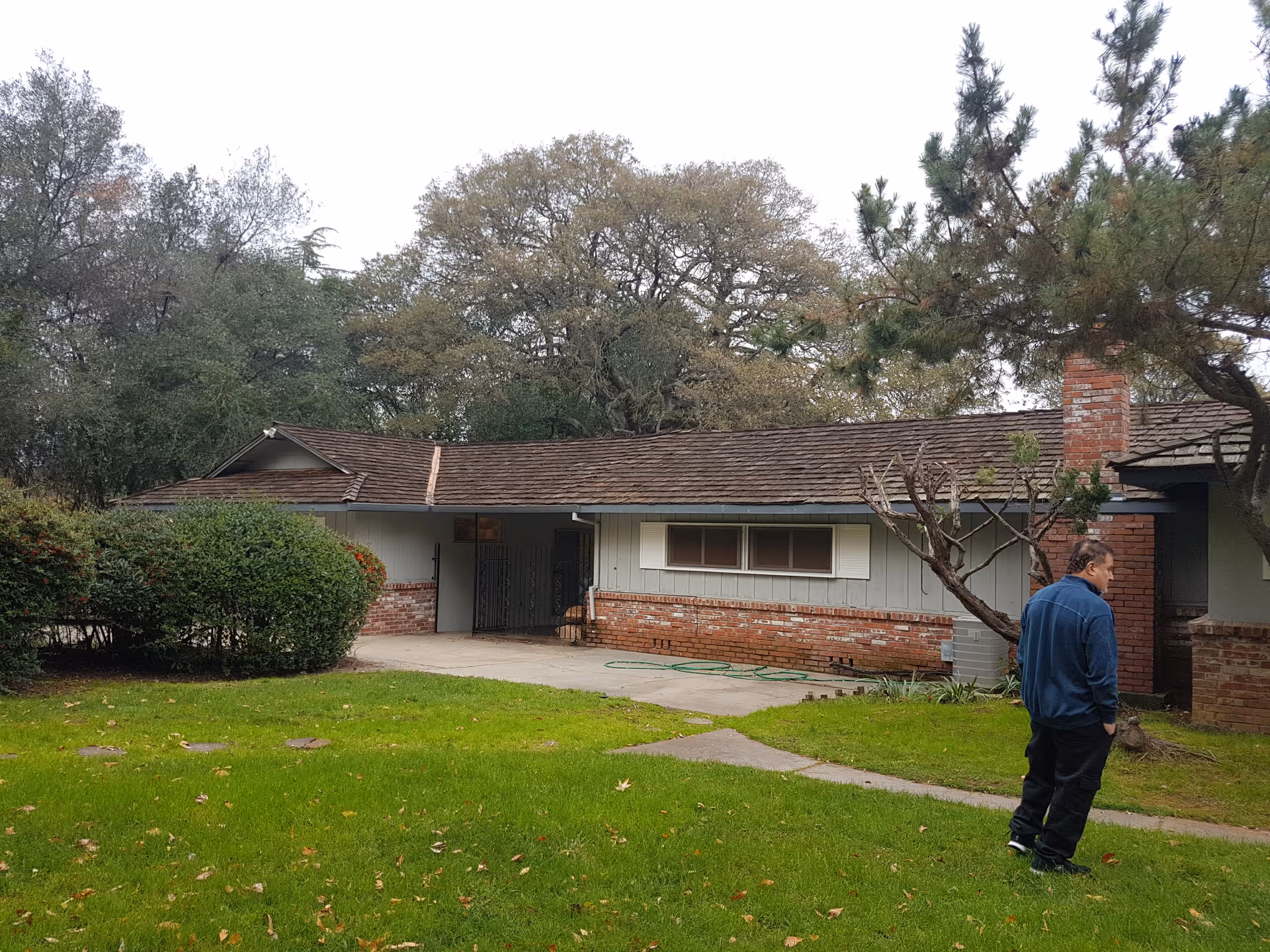 A single-story facility exterior with brick base, gray siding, and a man standing on the lawn.