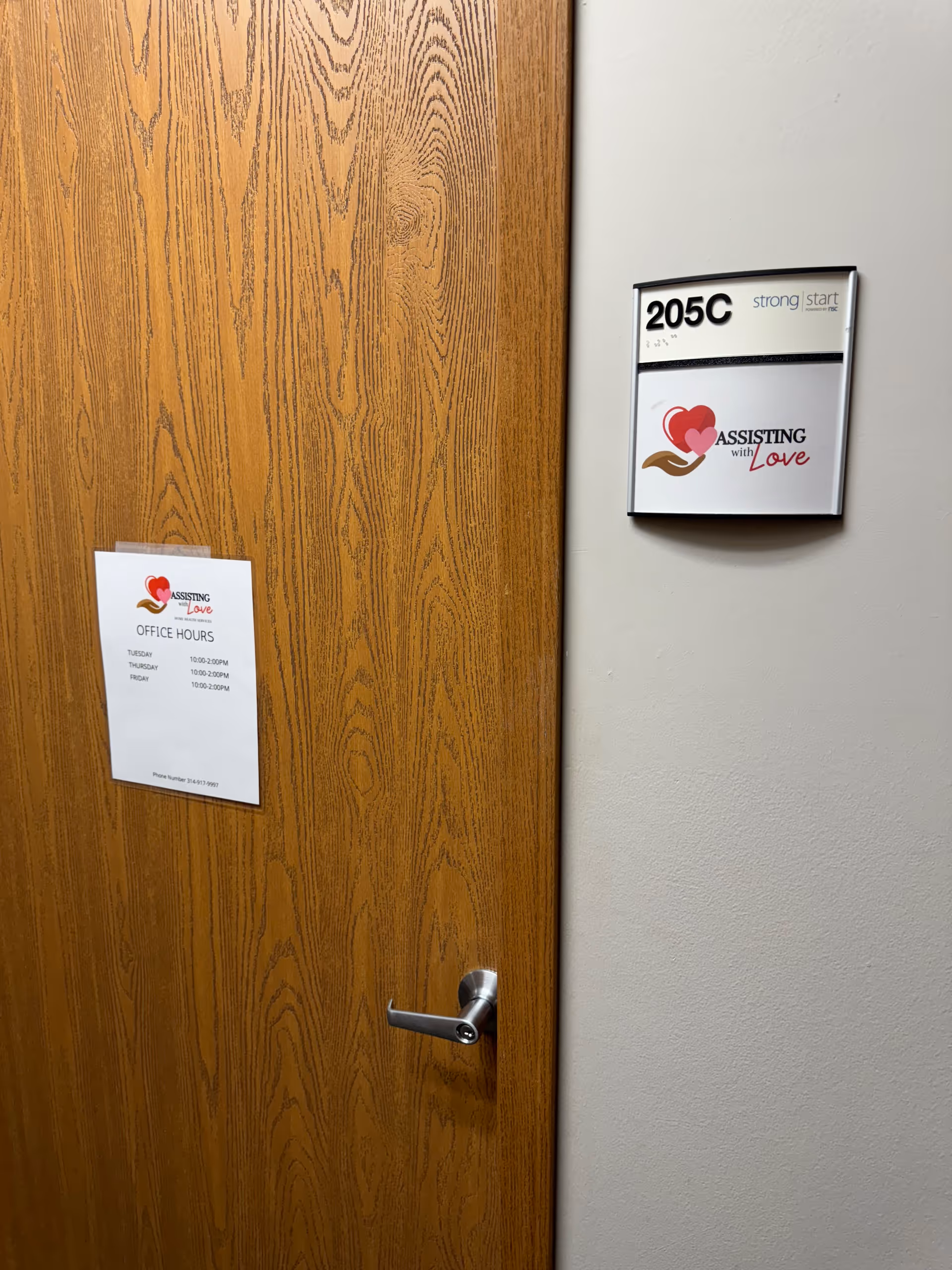 Wooden door with a sign reading Assisting with Love and room 205C on the wall.