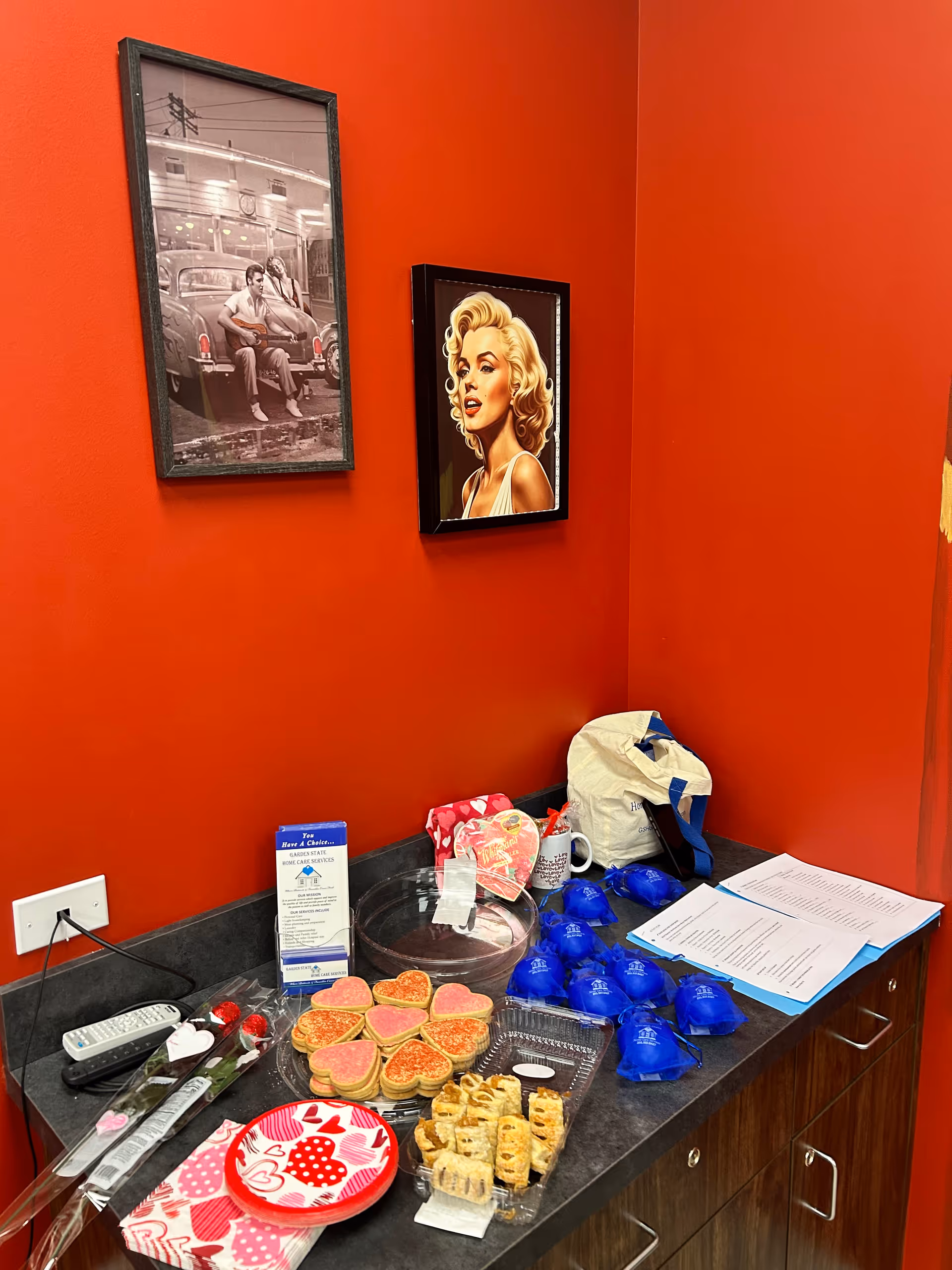 Red-walled interior snack station with cookies, pastries, napkins, and wall art.