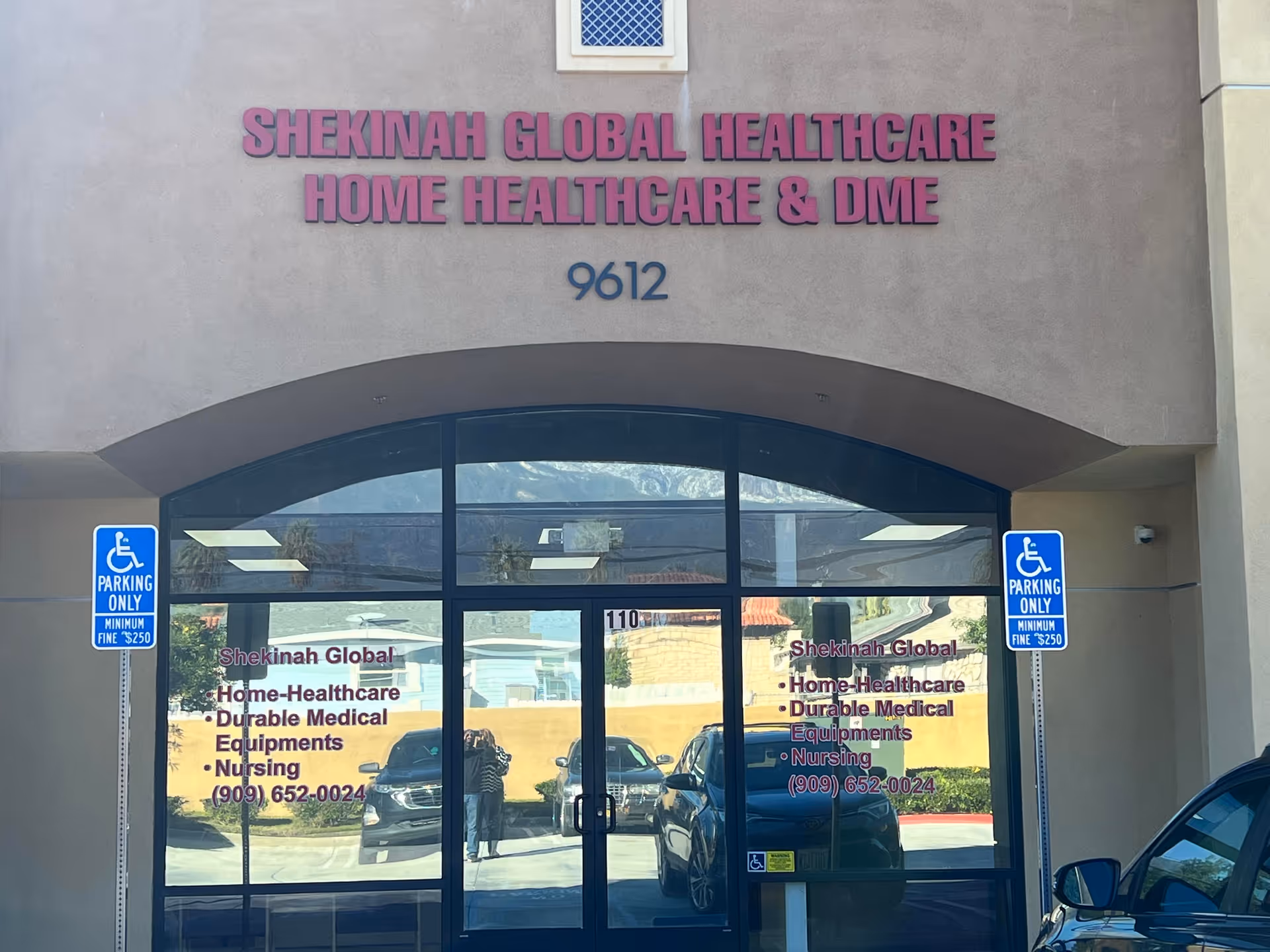 The facade of Shekinah Global Healthcare shows glass doors and handicap parking signs.