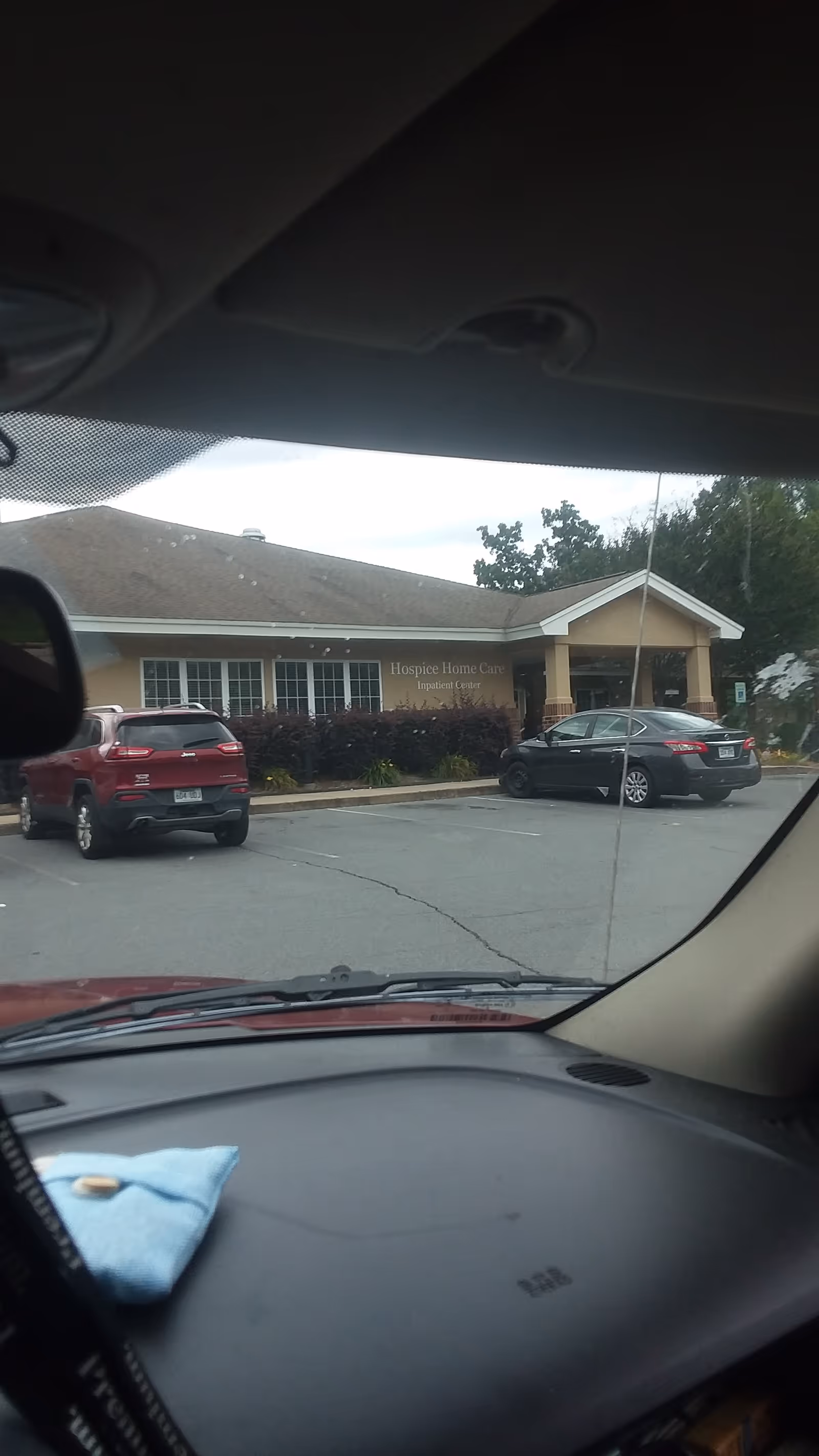 Front exterior of Hospice and Home Care building with parked cars in the lot.