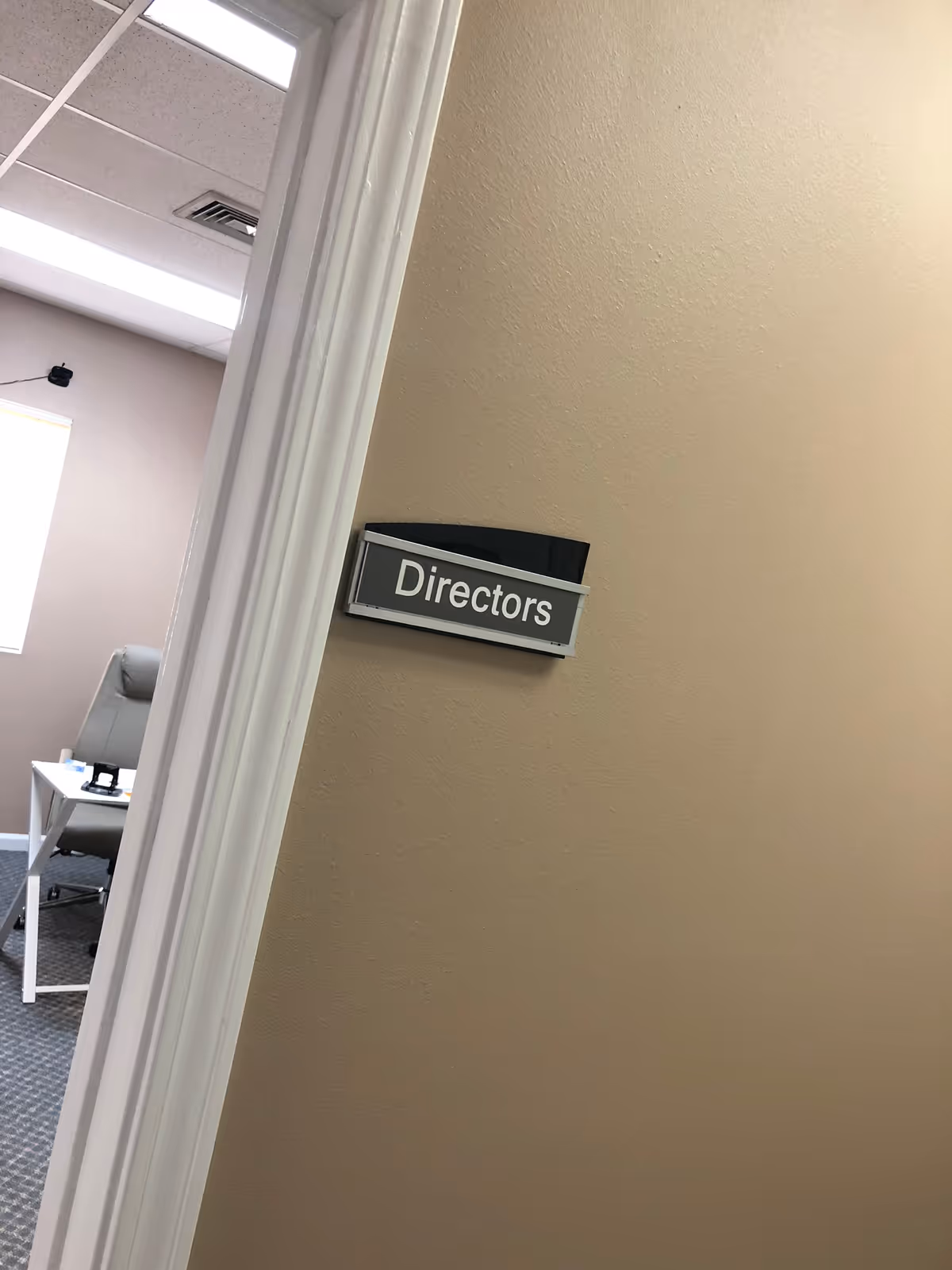 A beige wall with a Directors sign and a partial view of an office desk.