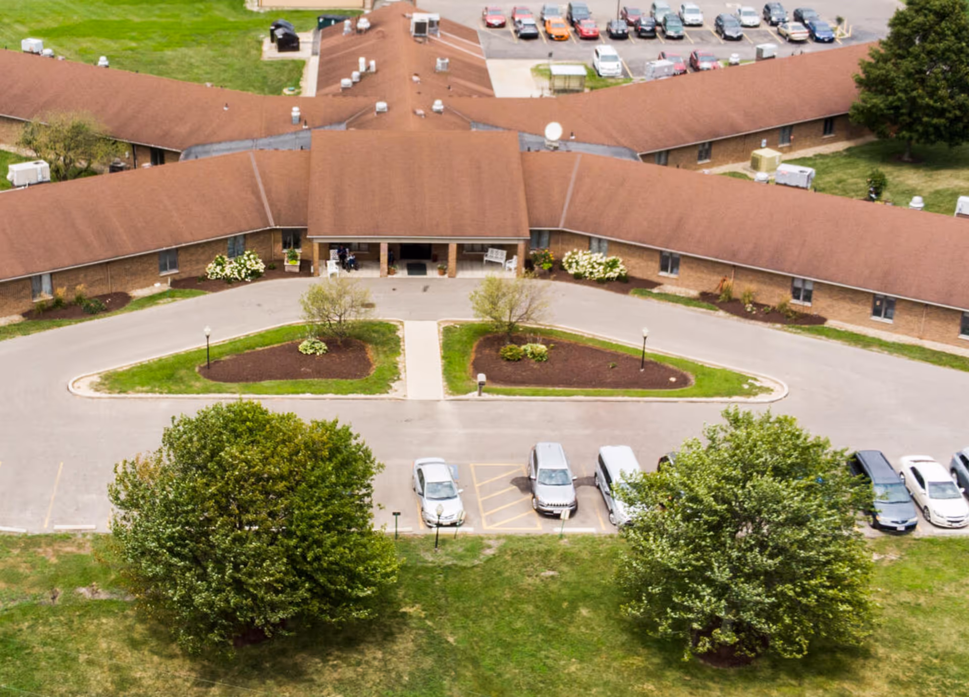 Aerial view of a brown-roofed senior living facility with a circular drive and parking lot.