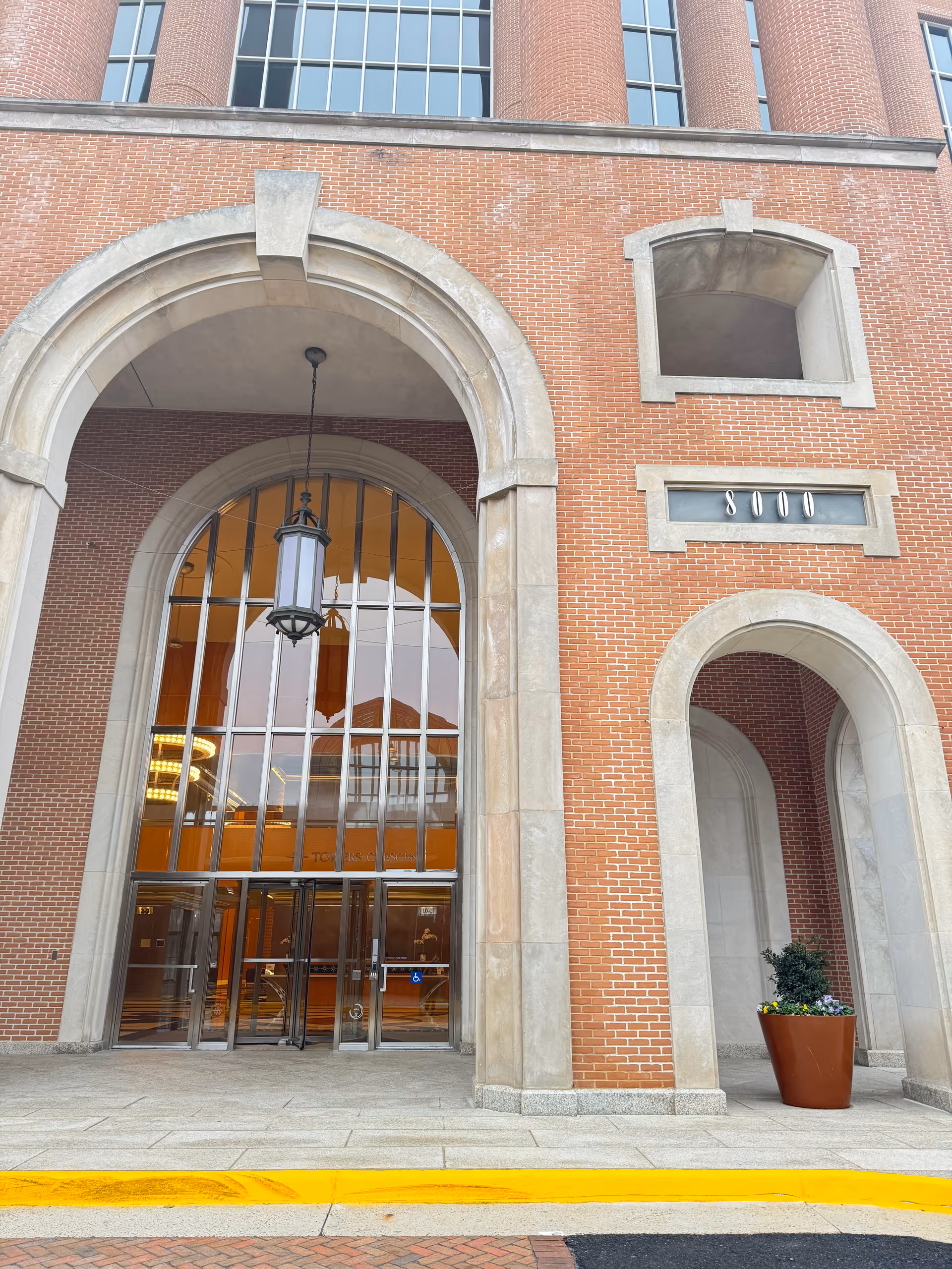 Brick building with arched glass entrance and hanging lantern at the front.